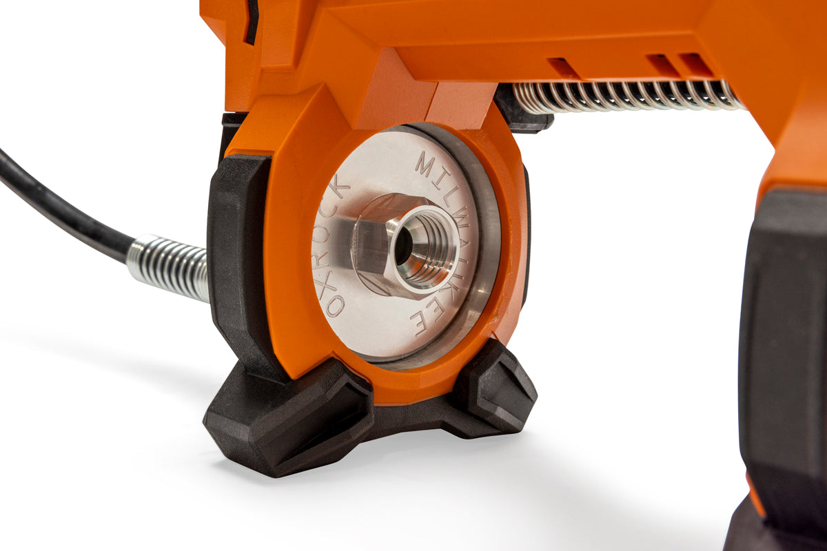 Close-up of a grease gun's metal connector with engraved text, attached to an orange housing with a black rubber base.