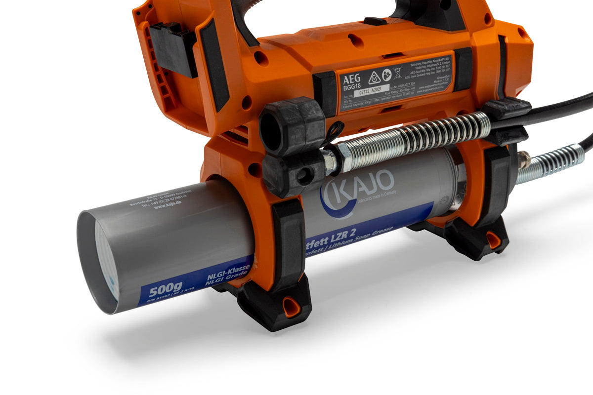 Side view of an orange cordless grease gun with a metal grease cartridge, black grip, and flexible hose for lubrication.